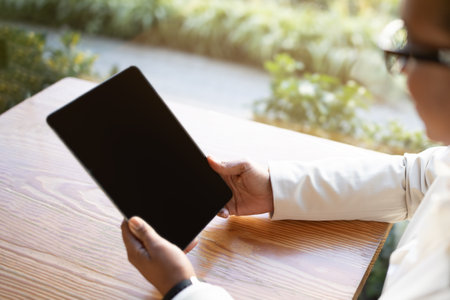 Millennial african american businesswoman reading on tablet with blank screen in cafeの写真素材