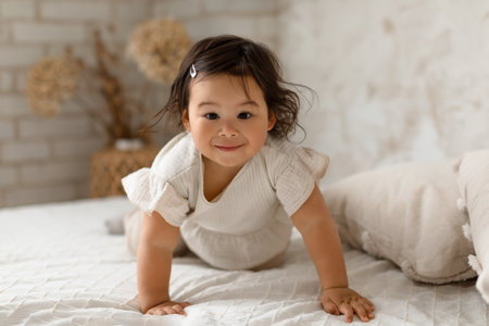 Japanese Toddler Infant Girl Crawling Looking At Camera In Bedroomの写真素材