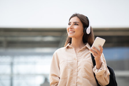 Satisfied glad millennial caucasian lady student in wireless headphones with phone listen musicの写真素材