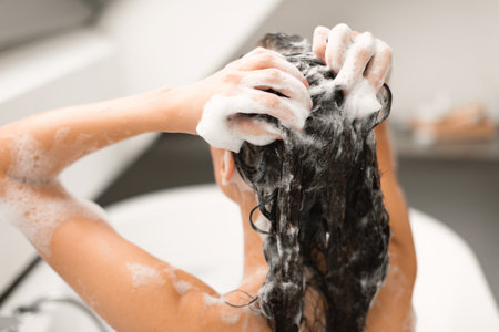 Female Applying Shampoo Washing Head Taking Bath Indoor, Back Viewの写真素材