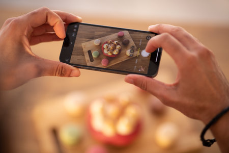 Cropped of male hands holding smartphone, taking photo of sweetsの写真素材