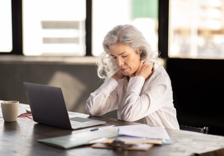 Unhappy Business Lady Touching Aching Neck Working Online In Officeの写真素材