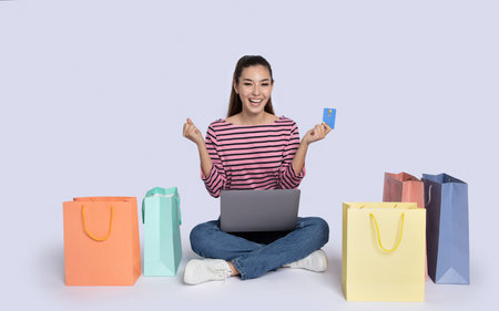 Stylish brunette woman with shopping bags using laptop, bank cardの写真素材