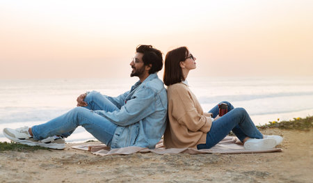Happy young diverse guy and female sitting back to back with outdoor, enjoy ocean, free timeの写真素材