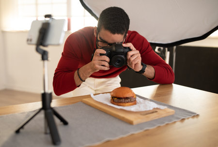 Food photographer taking photo of hamburger, using camera and phoneの写真素材