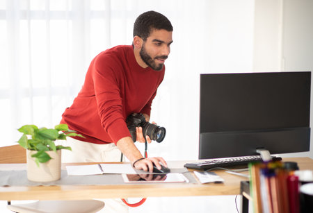 Man photographer working at photo studio, using camera and pcの写真素材