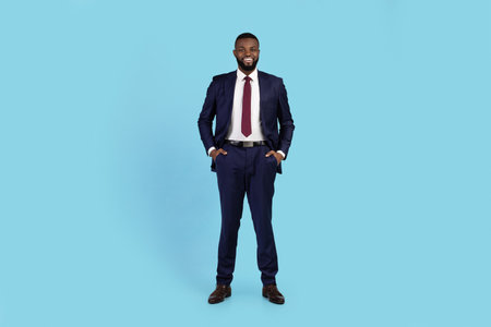 Portrait Of Handsome Young Black Businessman In Suit Standing On Blue Background