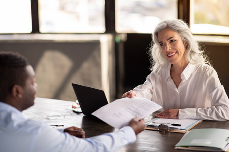 Male Job Applicant Giving CV To Female Manager In Officeの写真素材