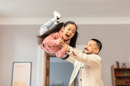 Happy Korean Father Lifting Kid Daughter In Air Playing Indoorの写真素材