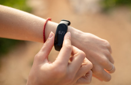 Young caucasian lady checks fitness tracker with empty screen, checks pulse, close up, unrecognizableの写真素材