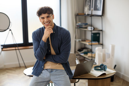 Happy Middle Eastern Guy Sitting On Desk At His Workplaceの写真素材