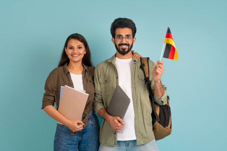Happy young indian couple students with flag of Germanyの写真素材