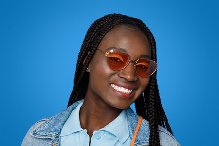 Portrait of smiling young black woman on blue studio background