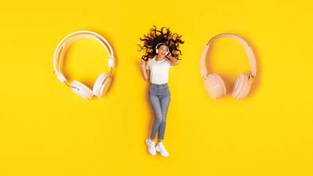 Woman Wearing Headphones Lying Near Huge Earphones Listening Music, Studioの写真素材