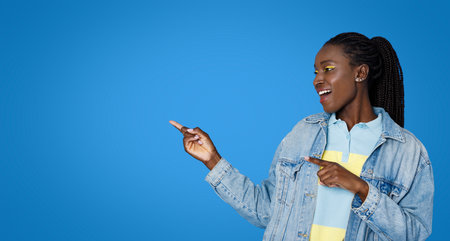 Emotional young black woman pointing at free space on blueの写真素材