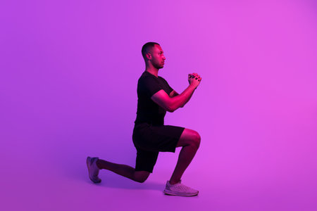 Athletic Black Man Exercising Doing Lunge Over Purple Studio Backgroundの写真素材