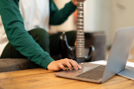 Teen Guy Using Laptop Holding Electric Guitar Sitting Indoor, Croppedの写真素材