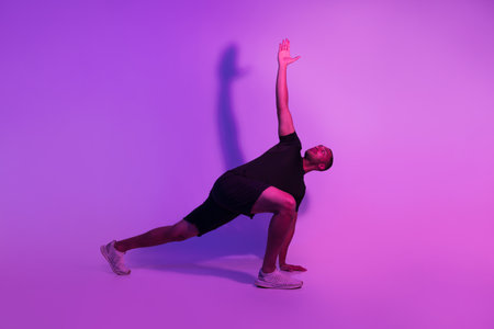 Black Fitness Man Practicing Yoga Over Purple Studio Background