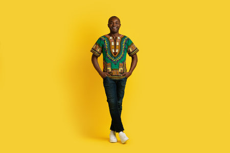 Positive attractive african man in traditional costume on yellowの写真素材