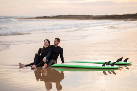 Romantic Young Couple Relaxing On Beach After Surfing Dayの写真素材