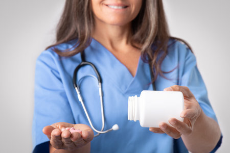 Therapist recommendation. Senior woman doctor in uniform pouring out pills from jar on hand, closeup, croppedの写真素材