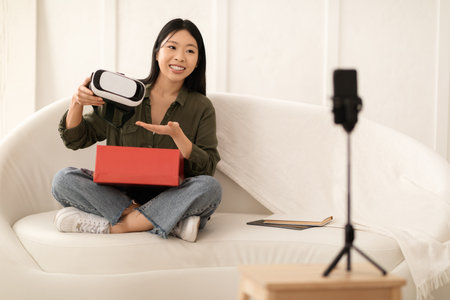 Asian woman blogger opening parcel and streaming, showing VR goggles