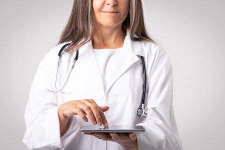 Professional woman doctor physician using digital tablet, reviewing medical record, digital document, cropped, closeupの写真素材