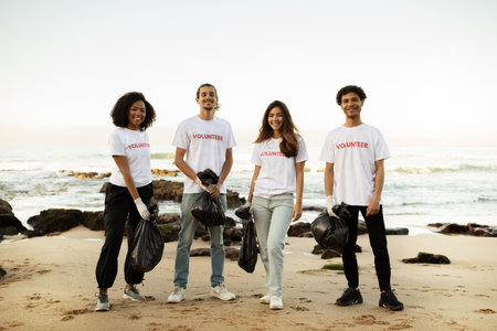 Smiling young different people volunteers in t-shirts and rubber gloves with garbage packages clean up garbageの写真素材