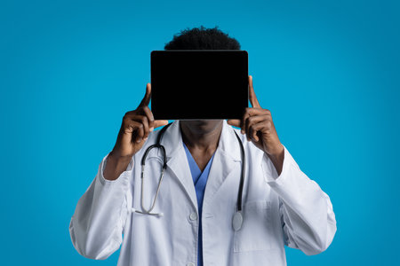 African american doctor holding digital tablet over his faceの写真素材