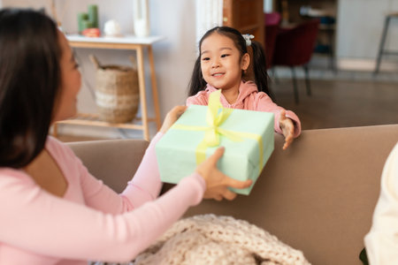 Asian Little Girl Giving Gift Box To Mommy At Homeの写真素材