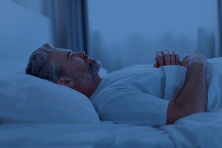 Sleepless middle aged man lying in bed at nightの写真素材