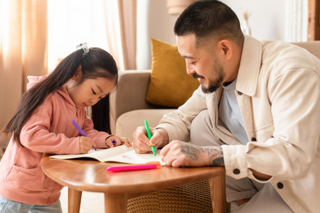 Chinese Dad Teaching Little Daughter To Write In Textbook Indoorsの写真素材