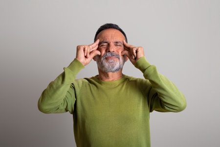 Unhappy sad caucasian elderly man in casual touching head, suffers from headache gray studio backgroundの写真素材