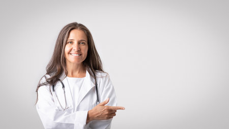Useful medical information. Portrait of confident senior woman doc pointing aside at copy space over light backgroundの写真素材