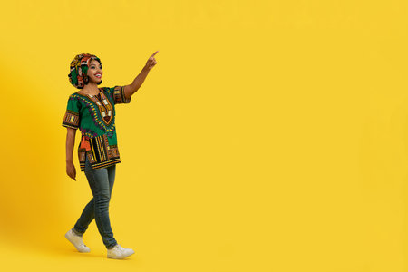 Pretty african lady in colorful outwear pointing at copy spaceの写真素材