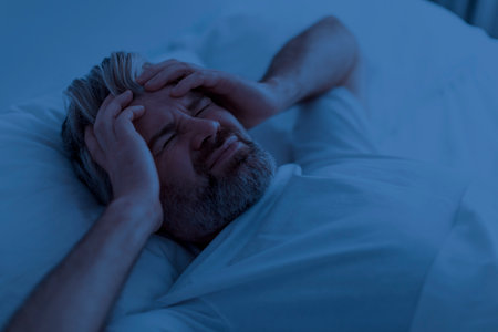 Top view of unhappy man suffering from headache at nightの写真素材