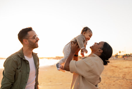 Familys beachside evening. Parents enjoying time with their little son, having fun on the beach, playing and laughingの写真素材