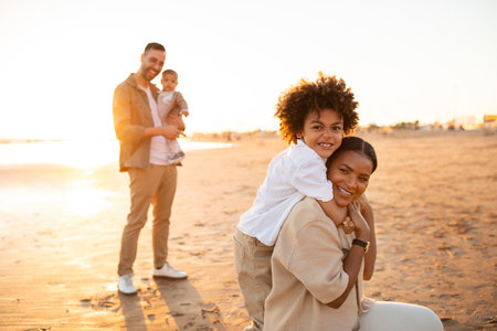 Beachside bonds. Mother and son embracing and smiling at camera, father with little son standing on backgroundの写真素材