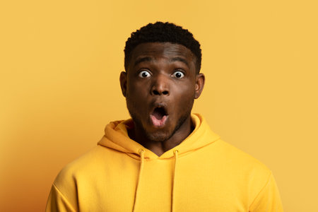 Shocked young black man grimacing on yellow, closeupの写真素材