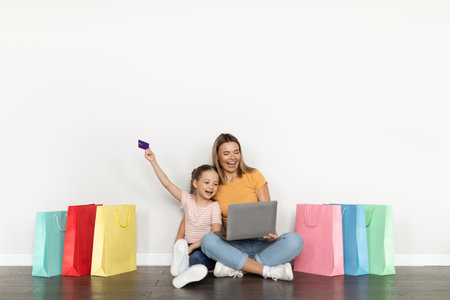 Mother And Daughter Shopping Online With Laptop And Credit Card At Homeの写真素材