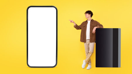 Man Leaning On Credit Card Pointing At Smartphone, Yellow Backgroundの写真素材