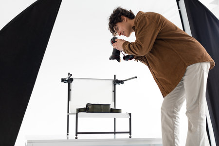 Creativity unleashed. Young photographer guy during content photoshoot, working in photostudio with modern equipmentの写真素材