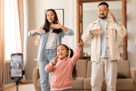 Cheerful Japanese Family Filming Their Dance Via Phone At Homeの写真素材