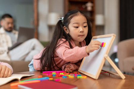 Asian Little Girl Learning Alphabet Playing With Magnetic Board Indoorsの写真素材