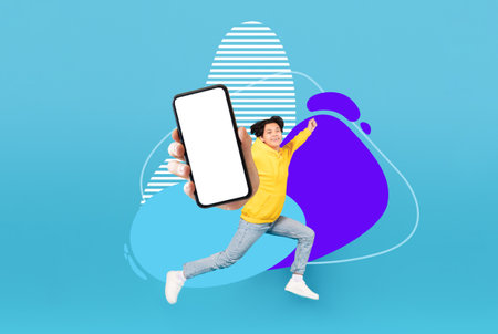 Asian Teen Guy With Blank Smartphone In Hand Jumping Over Abstract Backgroundの写真素材