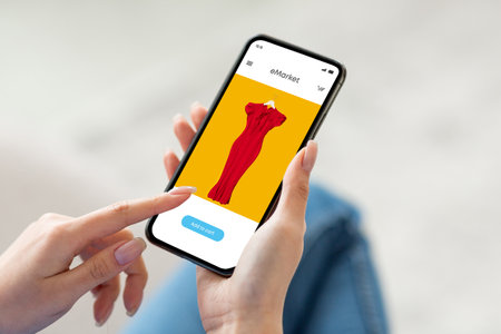 Millennial woman use modern phone with fashion store on screen, surfing in internet, app, enjoy online shoppingの写真素材