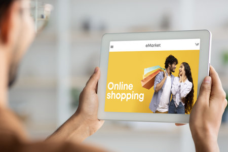 Young man use modern digital tablet with fashion store on screen, cropped, mobile app at home or officeの写真素材