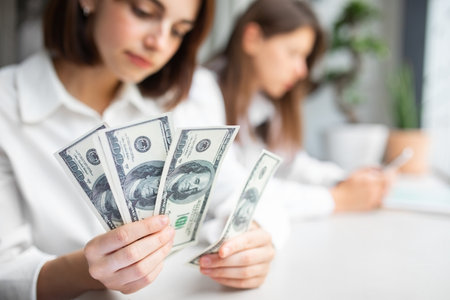 Young woman counting money, holding dollar banknotes cash, selective focus, closeup, free spaceの写真素材