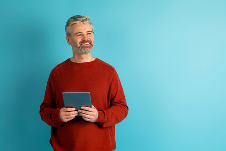 Happy mature man with digital tablet looking at copy space