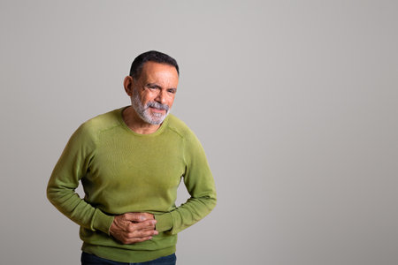 Sad despaired caucasian aged man in casual suffering from pain in stomach, belly, ulcerの写真素材